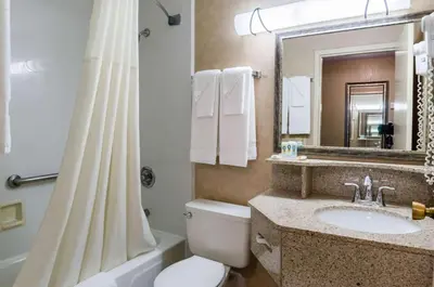 a bathroom with a toilet and a sink and a mirror at Quality Inn Chicopee-Springfield in Chicopee