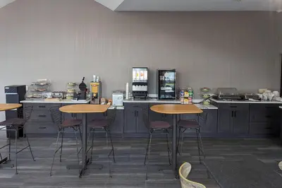 a kitchen with wooden tables and bar stools at Quality Inn & Suites Northampton - Amherst in Northampton