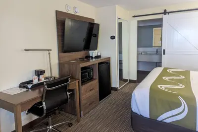 a hotel room with a bed and a desk and a television at Quality Inn & Suites Northampton - Amherst in Northampton