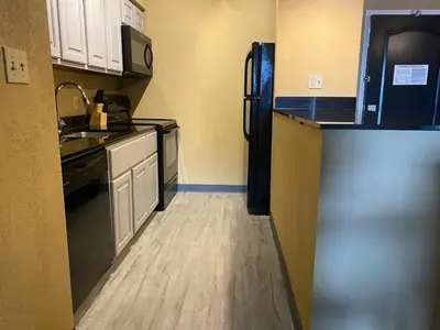 a kitchen with a black refrigerator and white cabinets at Park Manor Hotel in Clifton Park
