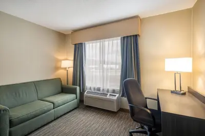 a hotel room with a couch and a desk and a window at Quality Inn & Suites Fishkill South near I-84 in Fishkill