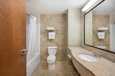 a bathroom with a toilet and a sink and a mirror at Quality Inn & Suites Fishkill South near I-84 in Fishkill