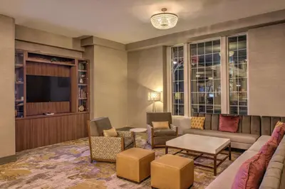 a living room with a couch and chairs and a tv at DoubleTree by Hilton Utica in Utica