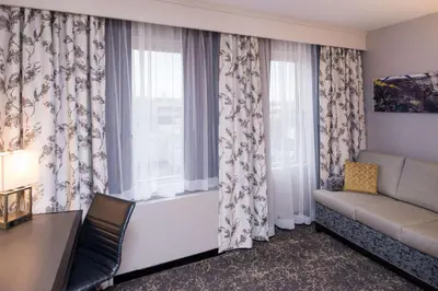 a living room with a couch and a window at DoubleTree by Hilton Utica in Utica