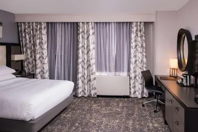 a hotel room with a bed and a desk and window at DoubleTree by Hilton Utica in Utica