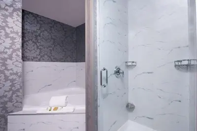 a bathroom with a shower with a tub and a sink at DoubleTree by Hilton Utica in Utica