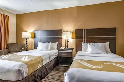 a hotel room with two beds and a chair at Quality Inn Schenectady - Albany in Schenectady