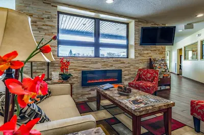 a living room with a fireplace and red flowers at Quality Inn Schenectady - Albany in Schenectady