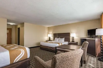 a hotel room with two beds and a desk and chairs at Quality Inn Schenectady - Albany in Schenectady