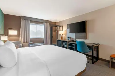 a hotel room with a large white bed and a desk at Comfort Inn & Suites Saratoga Springs in Saratoga Springs