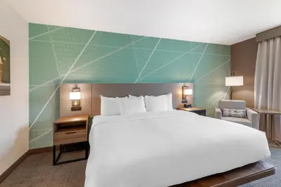 a hotel room with a large bed and a chair at Comfort Inn & Suites Saratoga Springs in Saratoga Springs