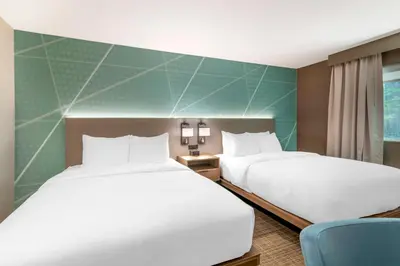 a hotel room with two beds and a chair at Comfort Inn & Suites Saratoga Springs in Saratoga Springs