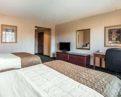 a hotel room with two beds and a desk and a television at The Marx Hotel - Downtown - University Area in Oneonta