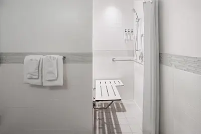 a white bathroom with a bench and towels at The Beekman Tower, Trademark Collection by Wyndham in New York