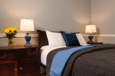 a bedroom with a bed with two lamps on a night stand at Rosemont Inn in Utica