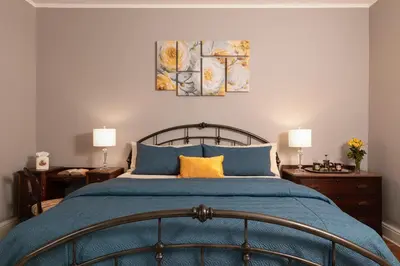 a bedroom with a blue bed with two lamps at Rosemont Inn in Utica