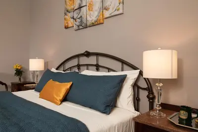 a bed with blue and white pillows and two lamps at Rosemont Inn in Utica