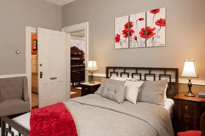 a bedroom with a bed with red flowers on the wall at Rosemont Inn in Utica
