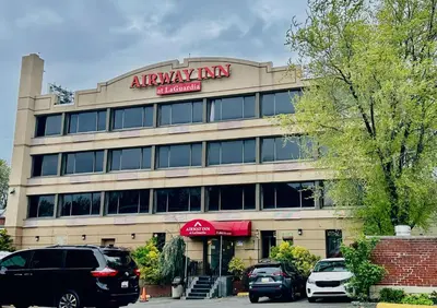 an office building with cars parked in front of it at Airway Inn in Queens