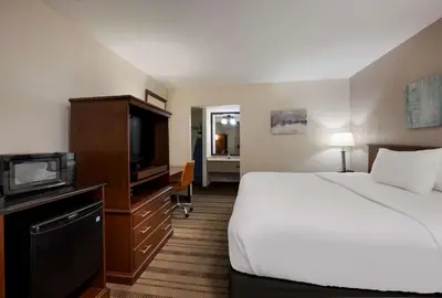 a hotel room with a bed and a flat screen tv at SureStay Plus by Best Western Woodbury Inn in Woodbury