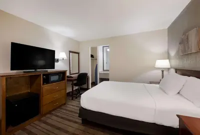 a hotel room with a bed and a flat screen tv at SureStay Plus by Best Western Woodbury Inn in Woodbury
