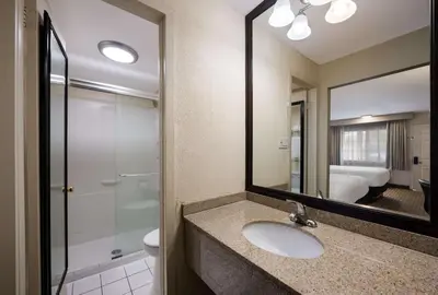 a bathroom with a sink and a shower and a mirror at SureStay Plus by Best Western Woodbury Inn in Woodbury
