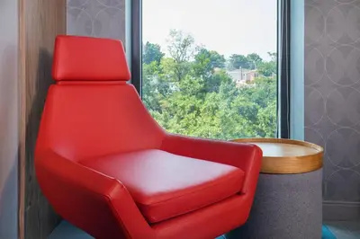 a red chair in a room with a window at Aloft New York LaGuardia Airport in Queens