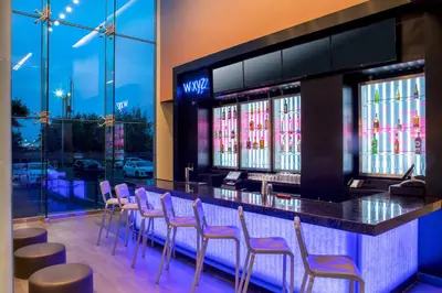 a bar in a restaurant with purple chairs at Aloft New York LaGuardia Airport in Queens