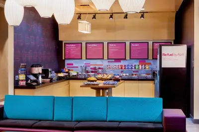 a restaurant with a blue couch in front of a counter at Aloft New York LaGuardia Airport in Queens