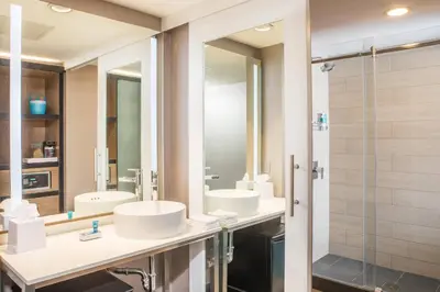a bathroom with two sinks and a shower at Aloft New York LaGuardia Airport in Queens