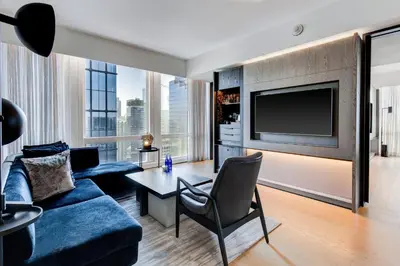 a living room with a blue couch and a tv at Equinox Hotel New York in New York