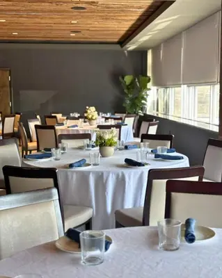 a dining room with tables and chairs with white table cloth at The Watershed Norwalk in Norwalk