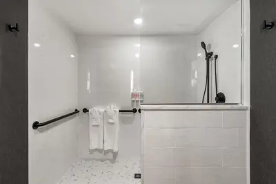a bathroom with a shower with white tiles and a shower at The Watershed Norwalk in Norwalk