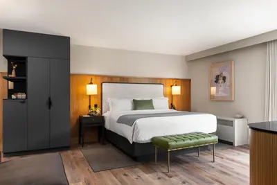 a bedroom with a large bed and a green stool at The Watershed Norwalk in Norwalk