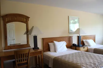 a hotel room with two beds and a desk and a mirror at Berkshire Travel Lodge in Canaan