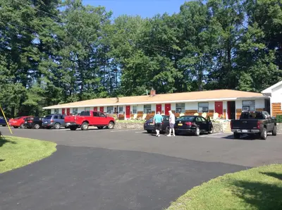 a building with cars parked in a parking lot at Robin Hood Motel in Saratoga Springs