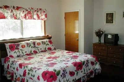 a bedroom with a bed with a floral bedspread and a window at Jenny's Country Manor in Stanfordville