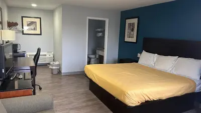 a hotel room with a bed with a yellow bedspread at Americas Best Value Inn Greenbush Albany in East Greenbush