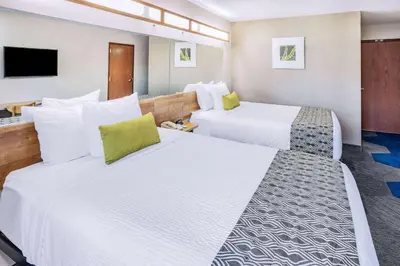 a hotel room with two beds and a tv at Microtel Inn & Suites by Wyndham Johnstown in Johnstown