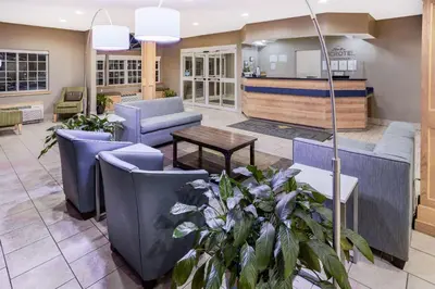 a lobby with blue chairs and a table at Microtel Inn & Suites by Wyndham Johnstown in Johnstown