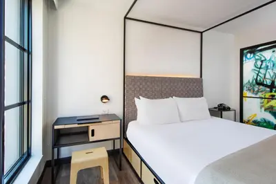 a bedroom with a bed and a desk and a bed and a window at Moxy NYC East Village in New York