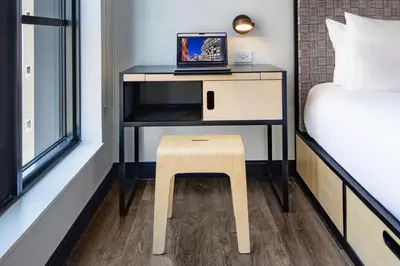 a small table with a laptop on a desk next to a bed at Moxy NYC East Village in New York