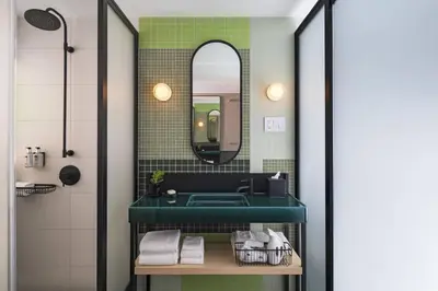 a bathroom with a green sink and a mirror at Moxy NYC East Village in New York