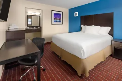 a hotel room with a bed and a desk and a computer at Travelodge by Wyndham Manhasset in Manhasset