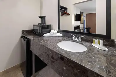 a bathroom counter with a sink and a mirror at Travelodge by Wyndham Manhasset in Manhasset