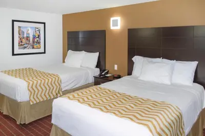 a hotel room with two beds with white sheets at Travelodge by Wyndham Manhasset in Manhasset