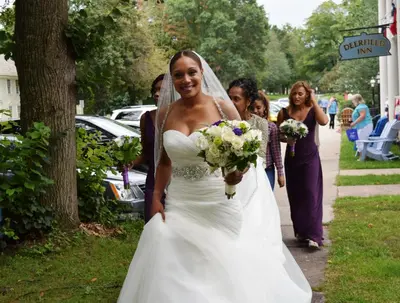 a bride walking down a sidewalk holding her bouquet at Deerfield Inn in Deerfield