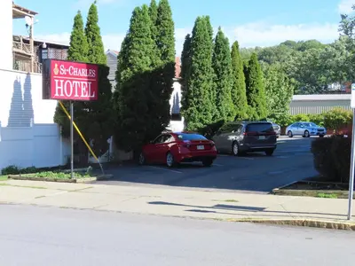 a sign for a hotel with cars parked in a parking lot at St Charles Hotel Downtown Hudson in Hudson