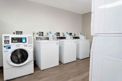 a laundry room with four washing machines and a refrigerator at Extended Stay America Suites - Hartford - Farmington in Farmington