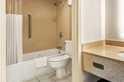a bathroom with a toilet and a tub and a sink at Howard Johnson by Wyndham Albany in Albany